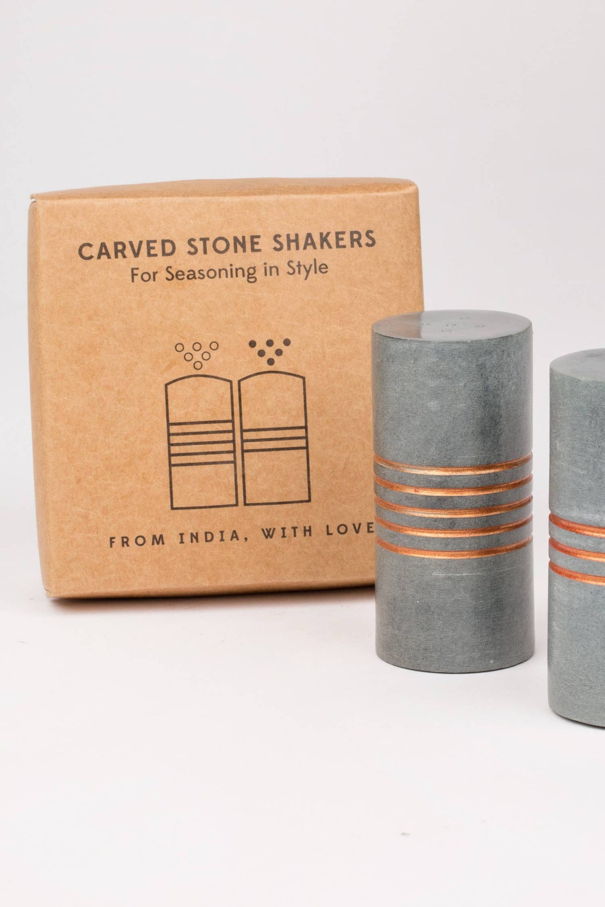 Salt and pepper stone shakers by Ten Thousand Villages, with textured stone surfaces and classic round shape.