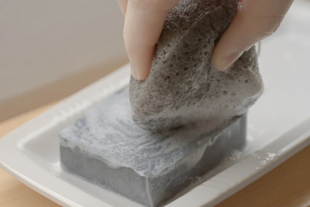 LUNA Charcoal Facial Sponge by No Tox Life with soap bar, showing a soft, textured charcoal facial cleansing sponge and soap on a white background.