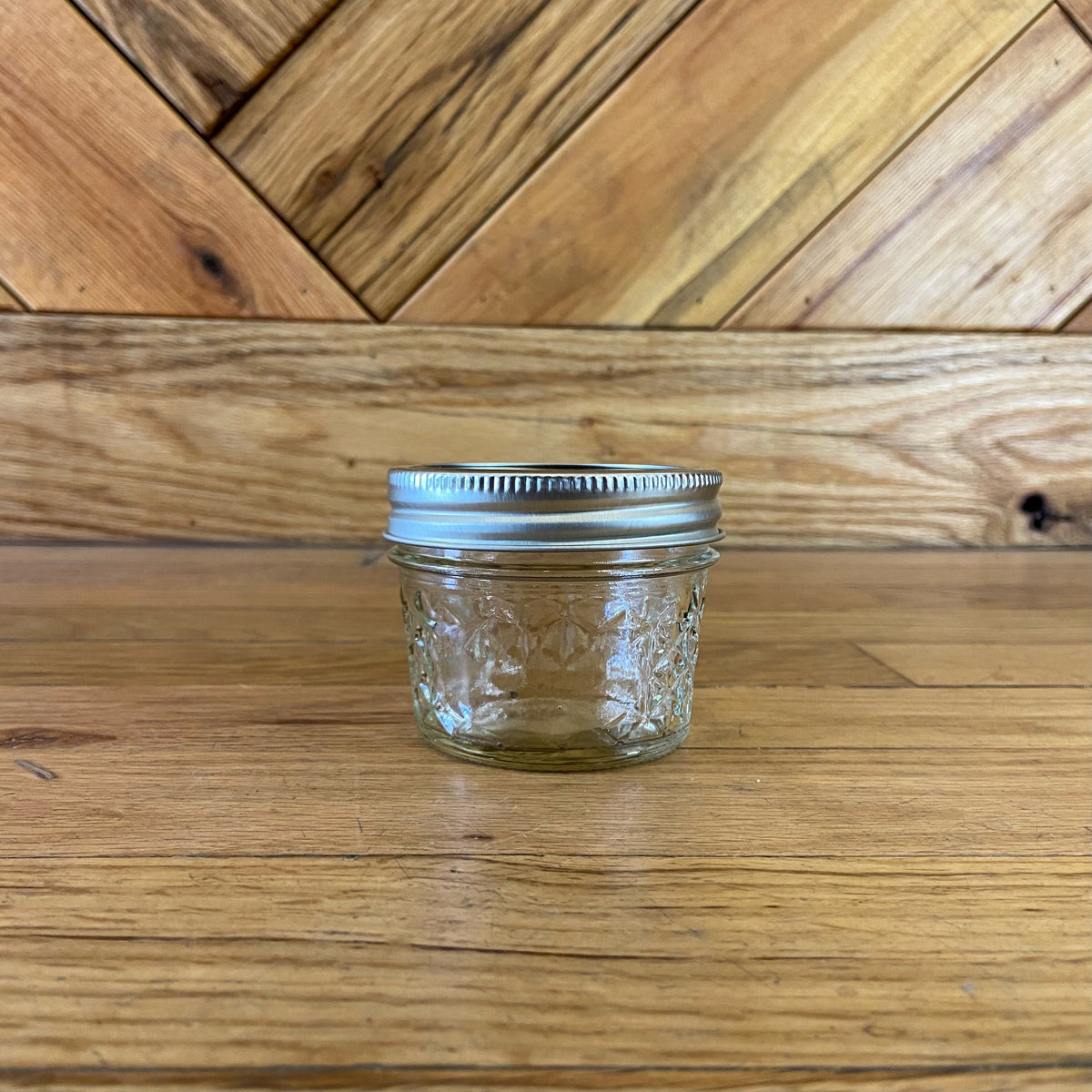 Four 4oz quilted Ball Mason glass jars with metal lids, showcasing their classic quilted design and transparent glass.
