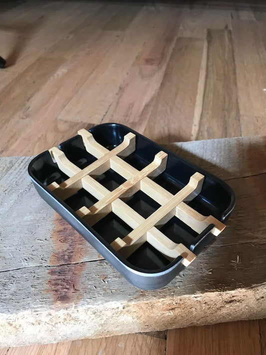 Black bamboo fiber soap dish with a sleek base, designed to hold soap bars in a modern bathroom setting.