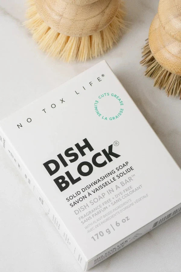 Solid dish soap block from No Tox Life with a brush for eco-friendly dishwashing in a natural kitchen setting.