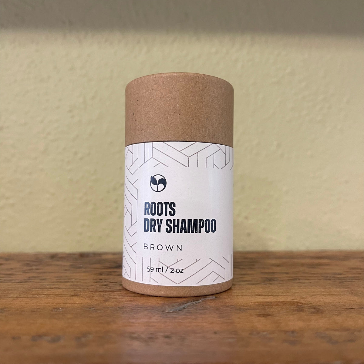 Natural Roots Dry Shampoo by ScentCerae in a 2oz shaker, showing the white powder inside the container.