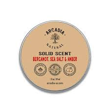 Natural solid perfume by Arcadia Naturals in a sleek metal case with a clear lid, showcasing the elegant fragrance container.