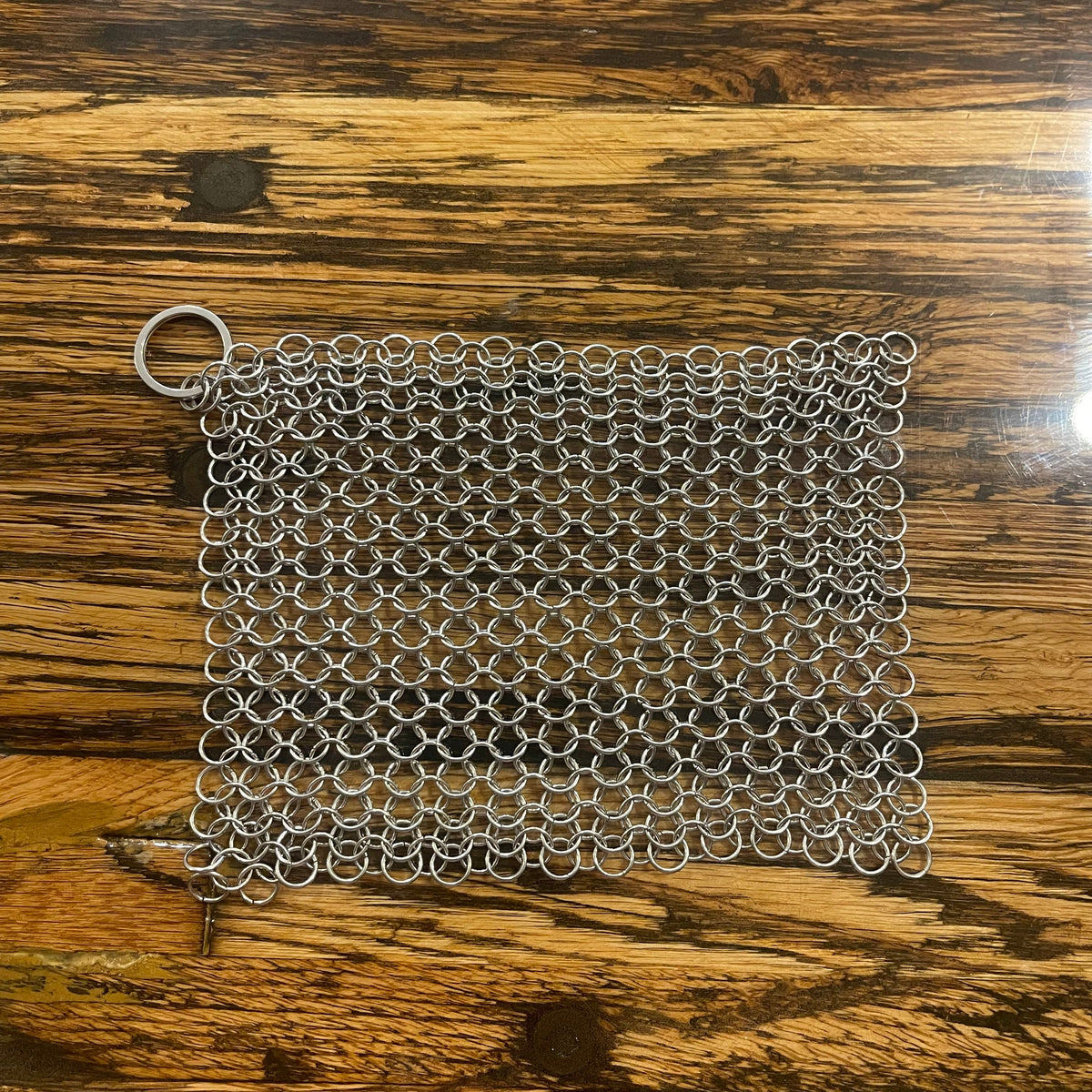 Stainless steel chain mail scrubber for cleaning cookware, made by OTB Refills, shown in a close-up image.