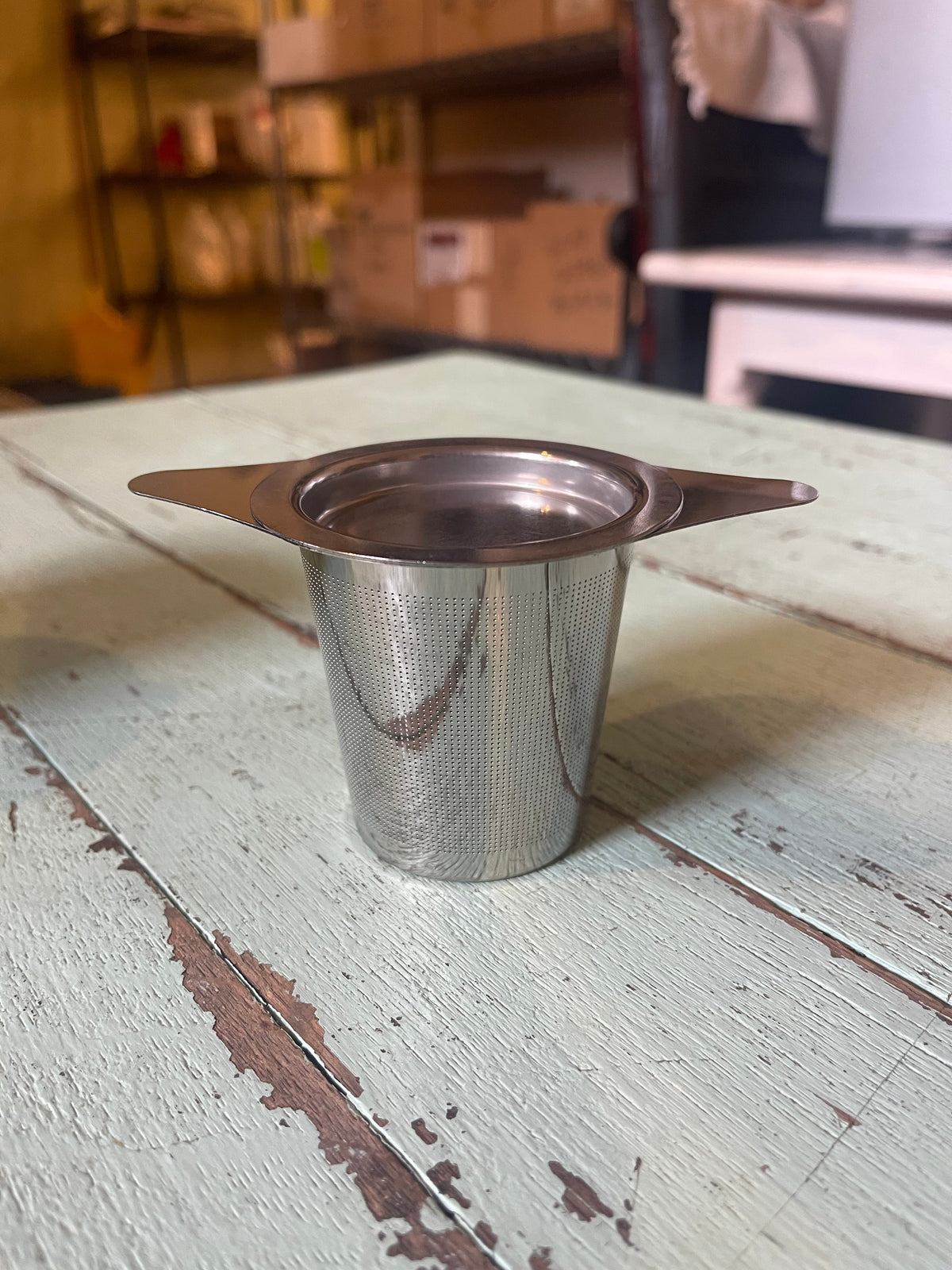 OTB Refills tea strainer and infuser in a cup, stainless steel mesh for brewing loose leaf tea, placed on a wooden surface.