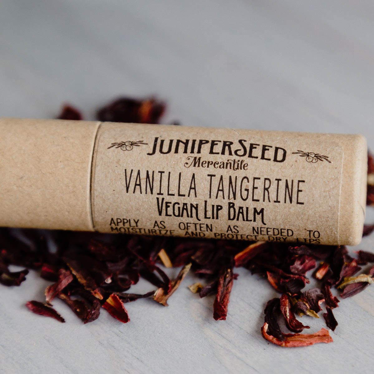 Juniperseed Mercantile Lip Balms displayed with natural packaging and ingredients on a neutral background.