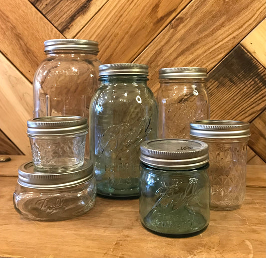 Clear glass Ball Mason jars with metal lids, ideal for storage or canning, showcasing their classic design and sturdy build.
