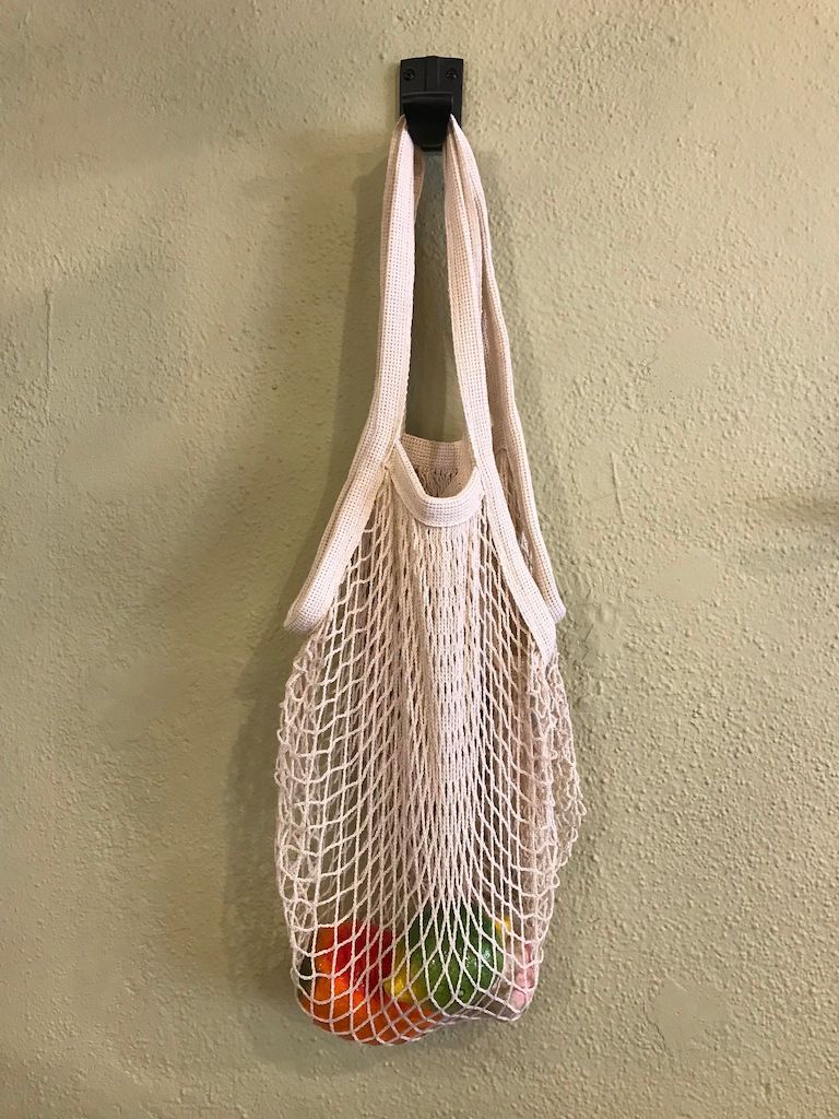 Organic cotton mesh tote bag with long handles, featuring a natural weave and shoulder straps for eco-friendly carrying.
