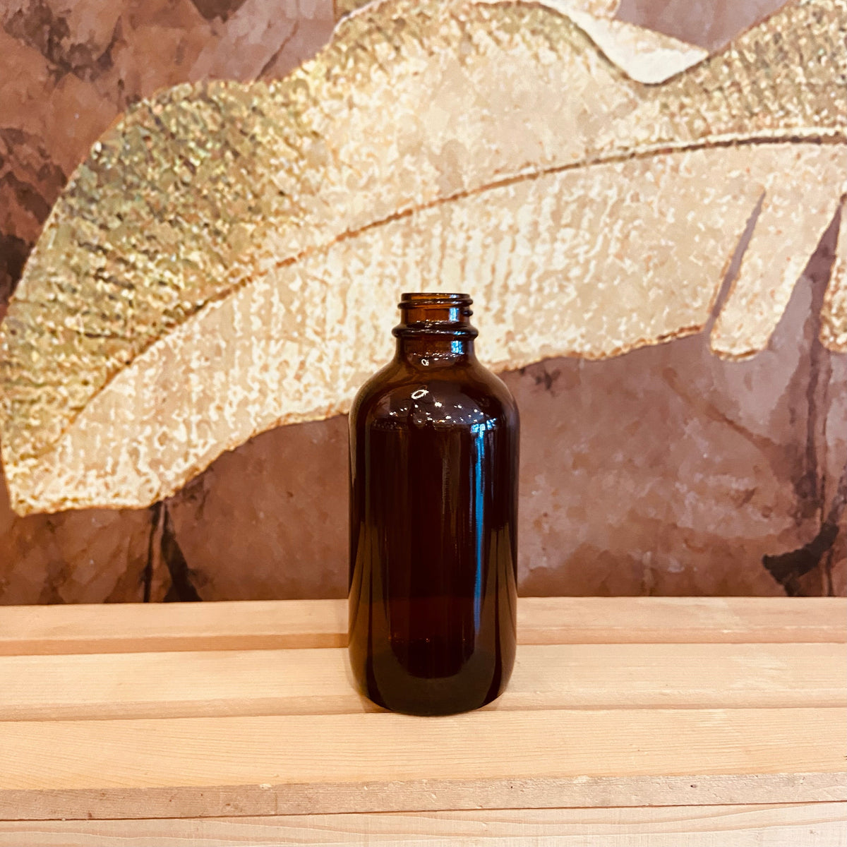 Clear amber glass Boston bottle, 4 oz size, by Premium Vials, featuring a smooth glass surface and a metal screw cap.